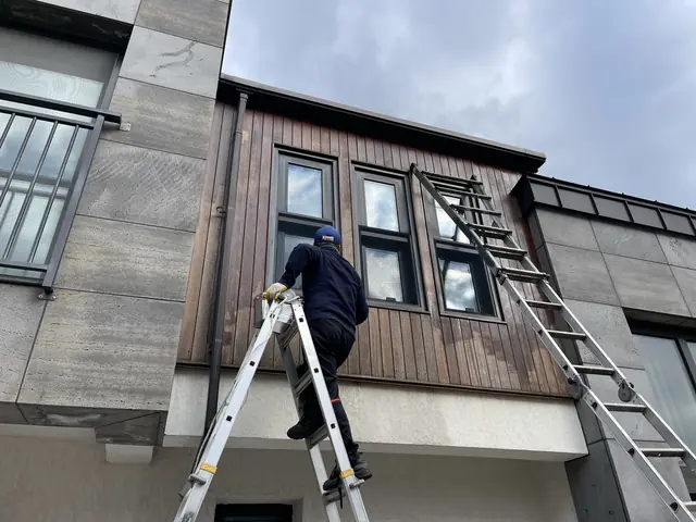 사다리를 이용해 목재 외벽을 작업하는 모습