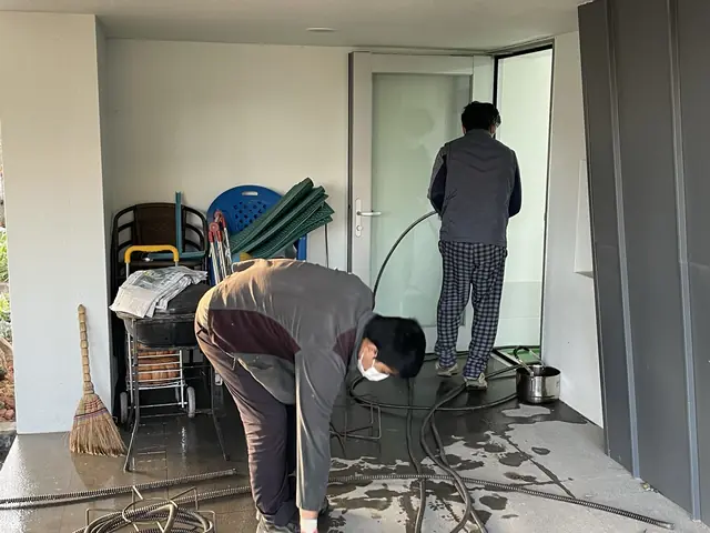 두 직원이 함께 바닥을 물청소하는 모습
