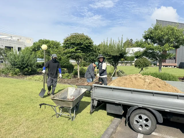 모래를 실은 차량과 손수레 옆에서 작업하는 직원들